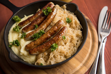 Kleine Bayrische Nürnberger Rostbratwürste mit Sauerkraut, Kartoffelpüree und Senf in rustikaler...