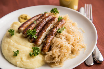 Kleine Bayrische Nürnberger Rostbratwürste mit Sauerkraut, Kartoffelpüree und Senf auf Holz Tisch Hintergrund