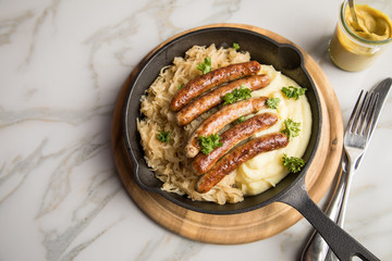 Kleine Bayrische Nürnberger Rostbratwürste mit Sauerkraut, Kartoffelpüree und Senf in rustikaler...