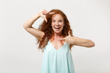 Fototapeta premium Young cheerful redhead woman girl in casual light clothes posing isolated on white wall background, studio portrait. People lifestyle concept. Mock up copy space. Making hands photo frame gesture.