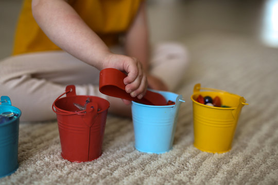 child girl on the floor plays with colorful cups