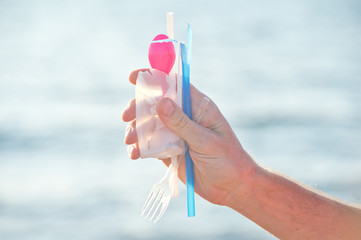 Environmental pollution problem.Concept of choice: save nature or continue to use disposable plastic. One hand holding beautiful shells, in the other plastic waste. 