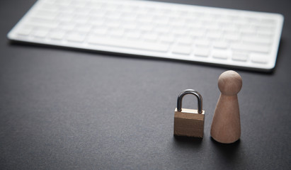 Human wooden figure with a padlock and computer keyboard. Personal data protection
