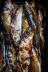Smoked herrings in black box on wooden background with copy space