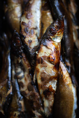 Smoked herrings in black box on wooden background with copy space
