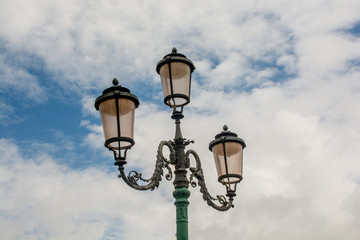 Venice old-fashioned retro lamps made of copper and pink glass with cloudy blue sky on the background
