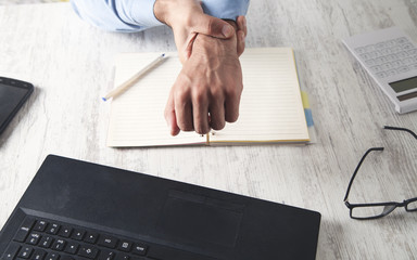Caucasian businessman suffering from wrist pain in office.