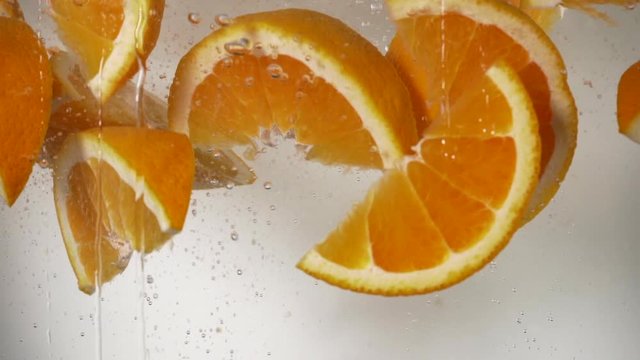 slow motion orange wedges dropping in water, refreshing orange falling in water white background. 
healthy vitamine c fruit