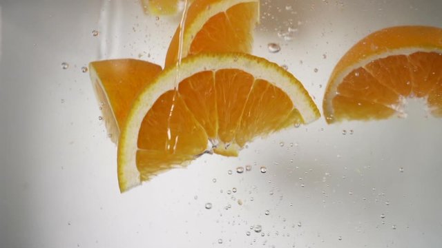 refreshing orange wedges falling in water, fresh vibrant orange color oranges. 
healthy fruit vitamin C