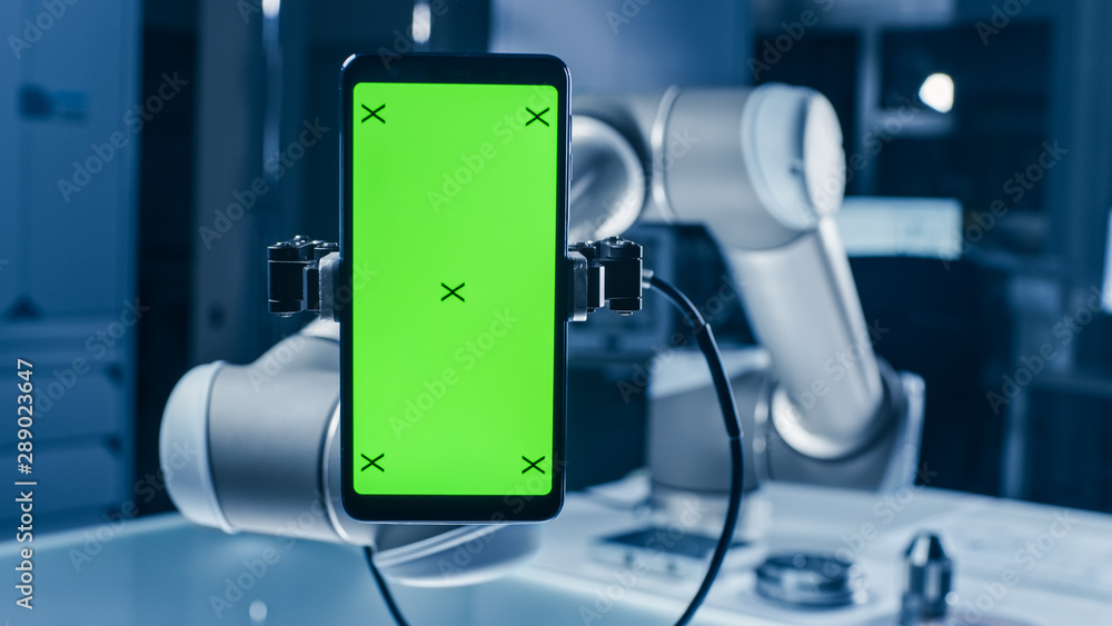 Poster real robot arm holding green mock-up screen smartphone device. industrial robotic manipulator end ef