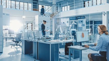 Diverse Team of Engineers Working on Computers, Program and Manipulate Robot Arm, Discuss Problems in Bright Industrial Robotics Technology and Design Office. Working in Research Facility.