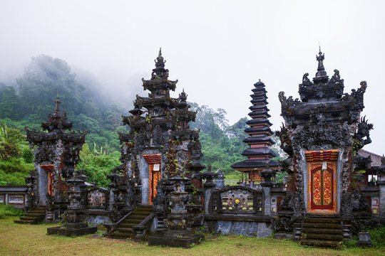 Foggy morning scenic view of ancient Balinese hindu temple at Buyan lake in mountain rainforest near Bedugul. Popular travel destinations, traditional art, culture, religion of Bali island, Indonesia