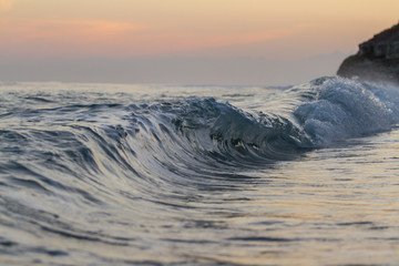 Tiny wave breaking on a beach at sunset