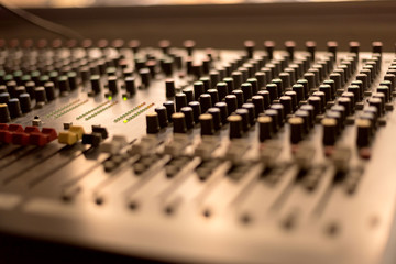 Fototapeta na wymiar Close up buttons of black audio mixer board console. Music equipment in sound audio room with abstract blurred seminar for business meeting in conference hall.