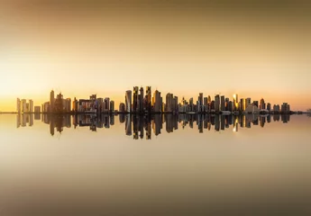 Fotobehang Die Skyline von Doha in Katar bei Sonnenuntergang  mit Reflektionen im Wasser © moofushi