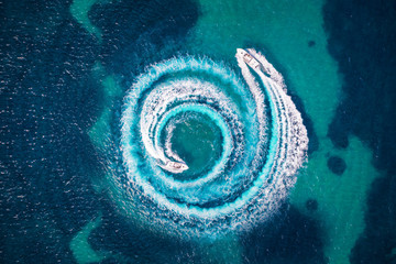 Zwei Motorboote formen einen Kreis aus Luftblasen und Wellen auf dem türkisem Meer - obrazy, fototapety, plakaty