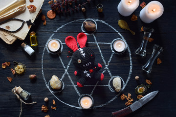 In Voodoo rabbit are needles pricked. Candles, pentagram, stones, love potion and old books on witch table. Occult, esoteric or divination concept. Mystic, Halloween and vintage background