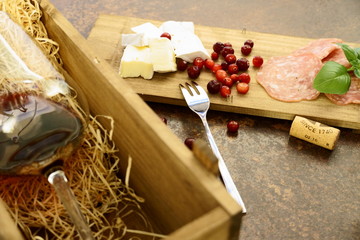 red wine glass with cheese and salami in wooden box on concrete table