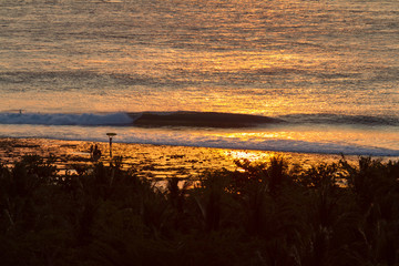 surfer silhouette and perfect breaking wave on a tropical island in Indonesia