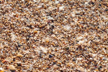 sea pebbles colored granite on the beach background stones. The shore of the beach with sand and pebbles washed by the waves of the sea.