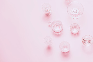 Many empty glasses on pink background. Top view, flat lay