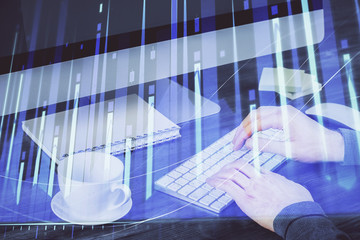 Multi exposure of graph with man typing on computer in office on background. Concept of hard work.