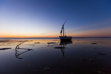 traditional african sail boat anchored on beach aat sunset - obrazy, fototapety, plakaty