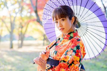 紅葉と和傘を持った着物の女性