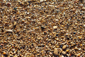 sea pebbles colored granite on the beach background stones. The shore of the beach with sand and pebbles washed by the waves of the sea.