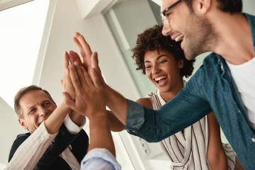 Foto op Plexiglas Celebrating success. Business people giving each other high-five and smiling while working together in the modern office © Friends Stock
