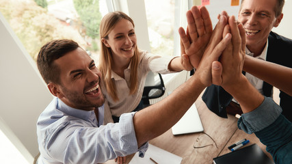 Successful team Business people giving each other high-five and smiling while working together in...