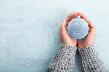 Christmas ball decor in women hand. Christmas greeting card. Woman's hands hold christmas or new year decorated gift.