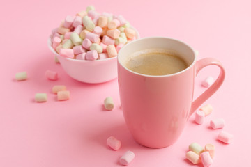 Pink mug with coffee and marshmallow in bowl on pink background
