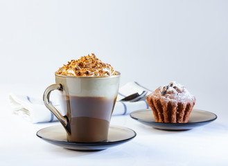 Coffee, cappuccino with whipped cream sprinkled with nuts, ground chocolate and cinnamon. Chocolate muffin in icing sugar. The photo.