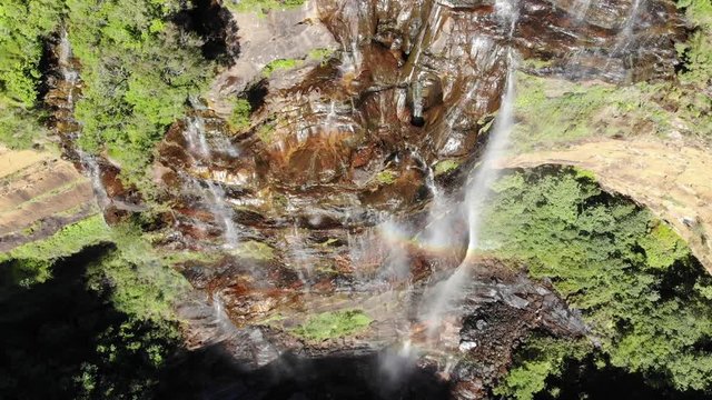 Wentworth Falls huge cliff waterfall with rainbow in New South Wales, Australia, aerial drone shot descending