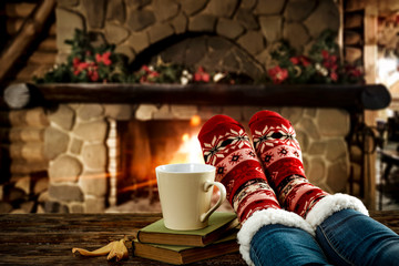 Woman legs with christmas socks and fireplace 