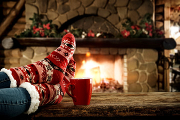 Woman legs with christmas socks and fireplace 