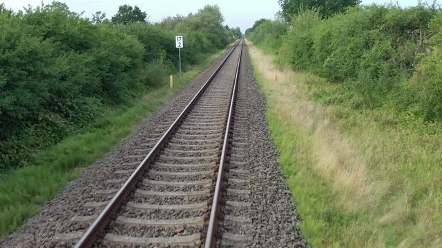 a drone flies in good weather at a very low altitude over railway tracks
