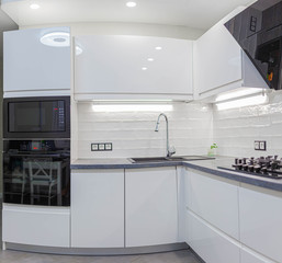 interior of the modern kitchen is white with black furniture and household appliances. high resolution image.