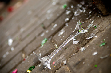 A broken champagne glass lies on the sidewalk. close up
