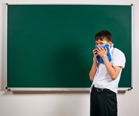 Portrait of funny pupil. School boy very emotional, having fun and very happy, blackboard...