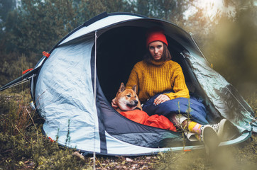 tourist hugging red shiba inu in camp tent on background foggy rain forest, hiker woman with puppy dog in mist nature trip, friendship love concept, girl resting dog together in campsite park