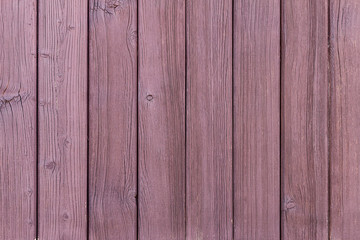 A wooden wall made of vertical old ragged painted reddish planks. Texture abstract background