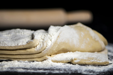 raw yeast puff pastry with flour on a dark background
