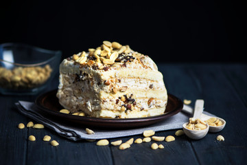 piece of cake stuffed with white cream and nuts on a plate on a dark background