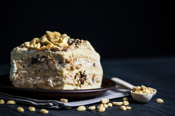 piece of cake stuffed with white cream and nuts on a plate on a dark background