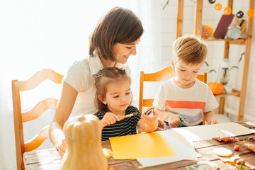 family mother and child daughter in hat witch are preparing for Halloween carve a pumpkin and...