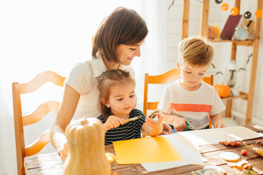 family mother and child daughter in hat witch are preparing for Halloween carve a pumpkin and decorate the house Happy Halloween concept