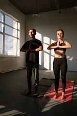 Fototapeta na wymiar Man and women holding hands in namaste gesture, ready to start practicing yoga meditation exercises at group training class 