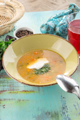 homemade vegetable soup with potatoes garnished with parsley and sour cream on blue wooden table